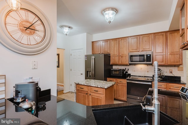 kitchen featuring a center island, tasteful backsplash, sink, dark stone counters, and appliances with stainless steel finishes