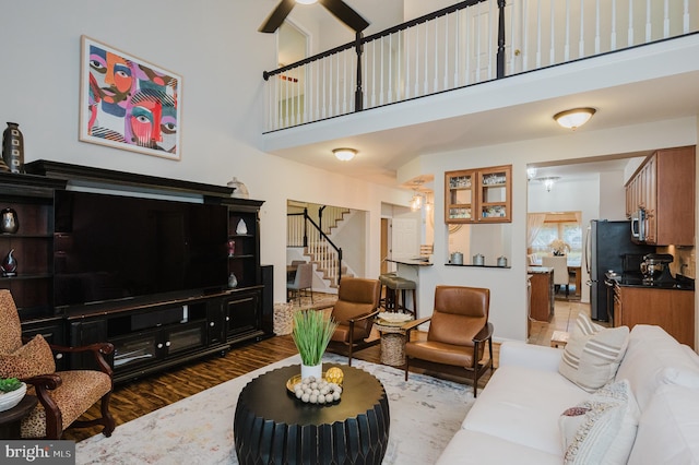 living room with ceiling fan, dark wood-type flooring, and a high ceiling