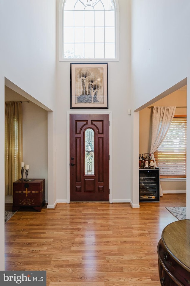 entryway with a high ceiling, wine cooler, and light hardwood / wood-style flooring