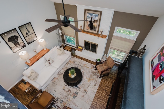 living room featuring ceiling fan, a fireplace, hardwood / wood-style floors, and high vaulted ceiling