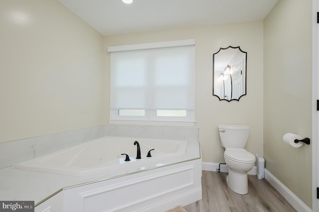 bathroom featuring hardwood / wood-style flooring, a tub to relax in, and toilet