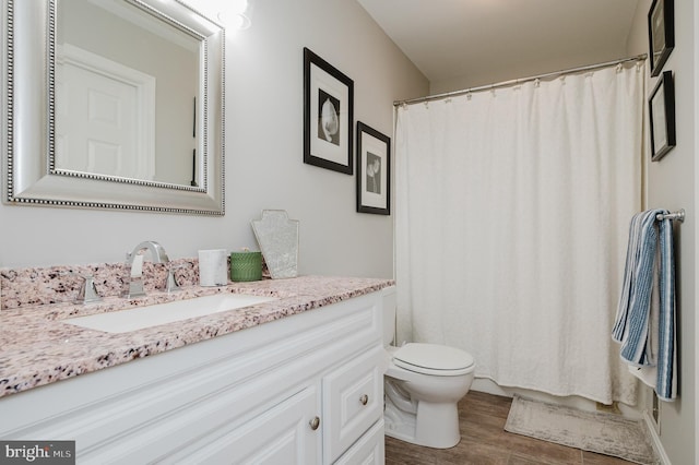 bathroom featuring hardwood / wood-style flooring, toilet, vanity, and curtained shower