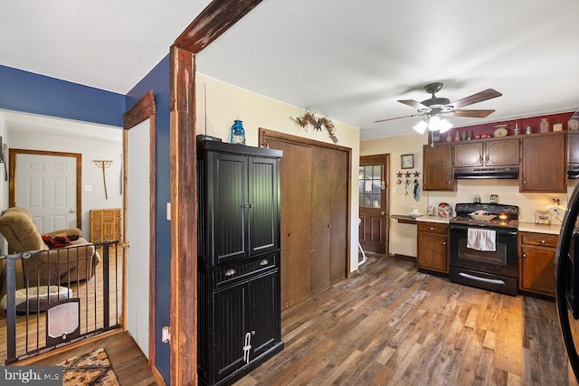 kitchen with black range with electric cooktop, dark brown cabinets, ceiling fan, stainless steel dishwasher, and hardwood / wood-style floors