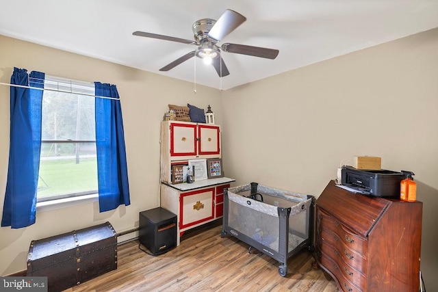 interior space with hardwood / wood-style floors, ceiling fan, and a baseboard radiator