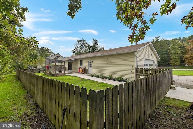 rear view of house featuring a lawn, an outbuilding, a deck, and a garage