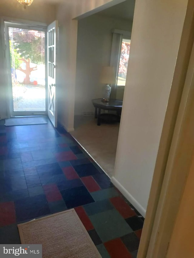 corridor featuring dark colored carpet and plenty of natural light