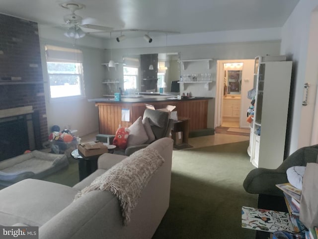 carpeted living room with ceiling fan and a brick fireplace