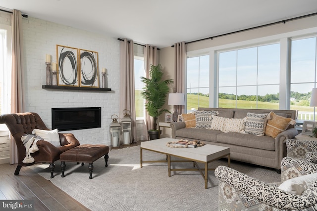 living room with a brick fireplace and hardwood / wood-style flooring