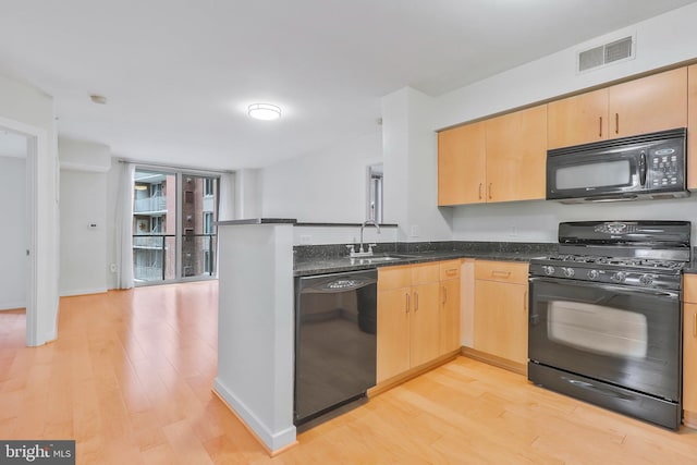 kitchen featuring light wood-type flooring, black appliances, light brown cabinetry, and sink