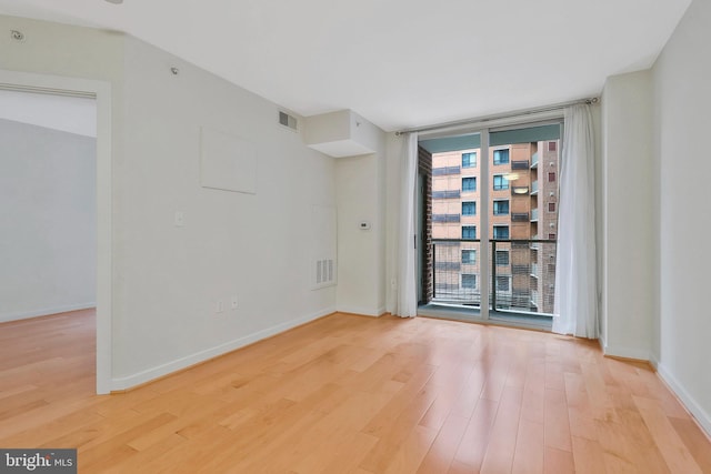 empty room featuring floor to ceiling windows and light hardwood / wood-style floors