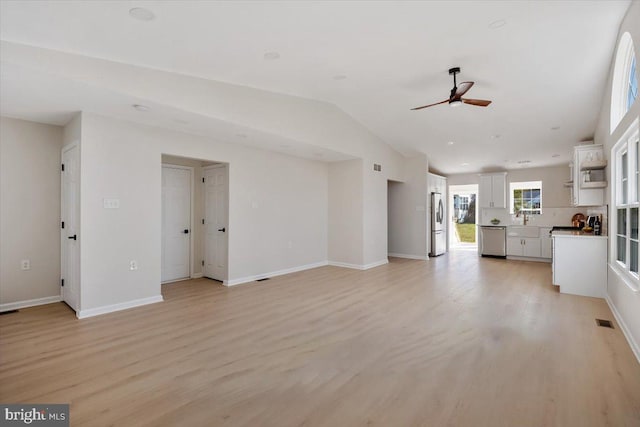 unfurnished living room featuring baseboards, a ceiling fan, visible vents, lofted ceiling, and light wood finished floors