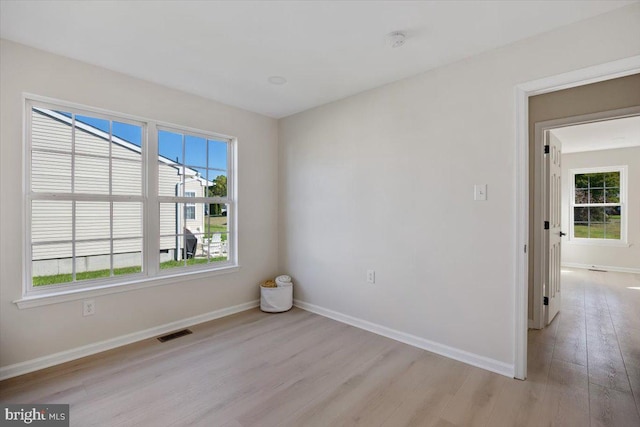 spare room with light wood-style floors, visible vents, and baseboards