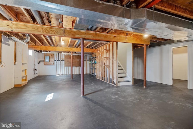 unfinished basement featuring stairway and electric panel