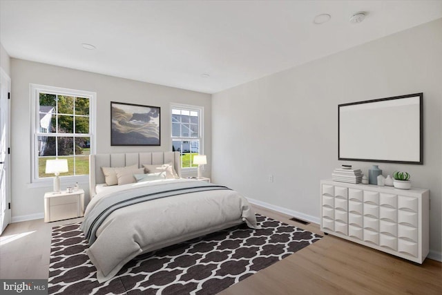 bedroom featuring visible vents, baseboards, and wood finished floors