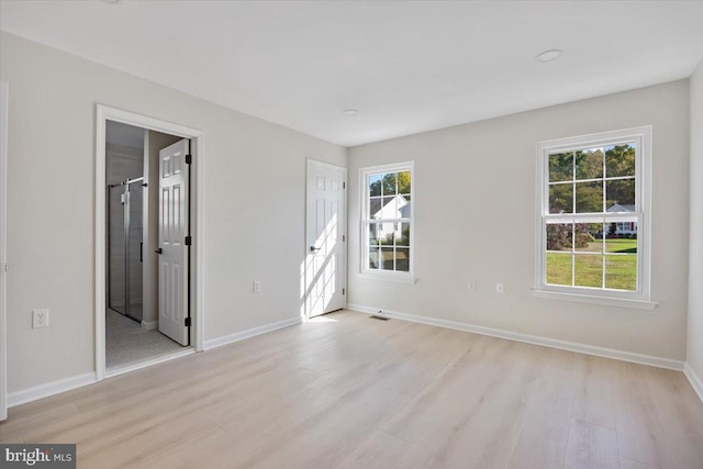 unfurnished bedroom featuring visible vents, light wood-style flooring, ensuite bath, and baseboards