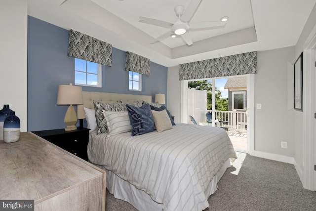 carpeted bedroom featuring ceiling fan, a raised ceiling, access to exterior, and multiple windows