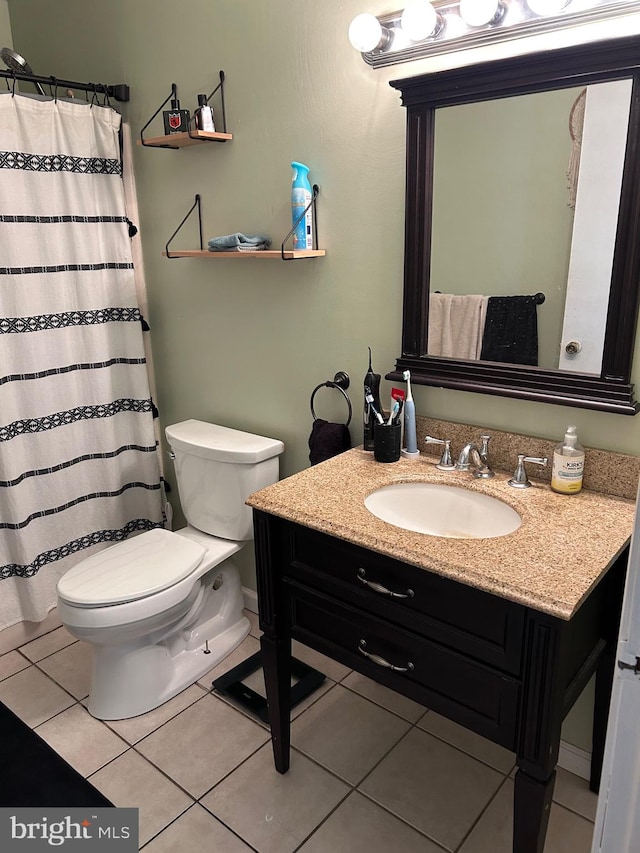 bathroom with toilet, vanity, and tile patterned floors