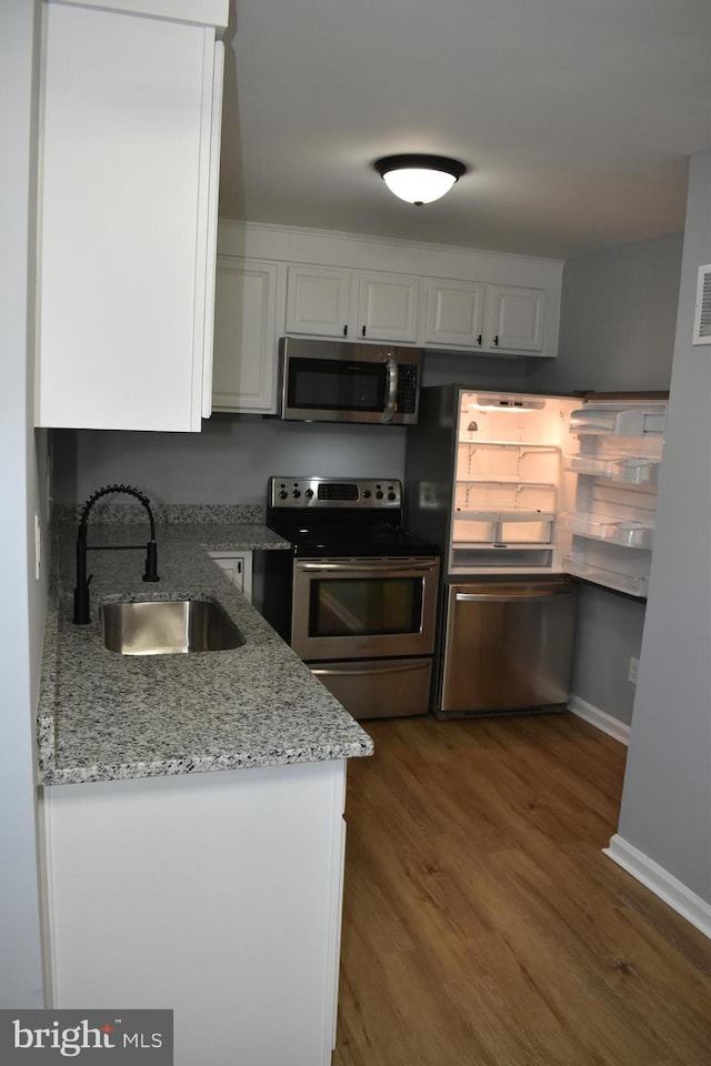 kitchen with white cabinets, sink, dark hardwood / wood-style floors, light stone countertops, and appliances with stainless steel finishes