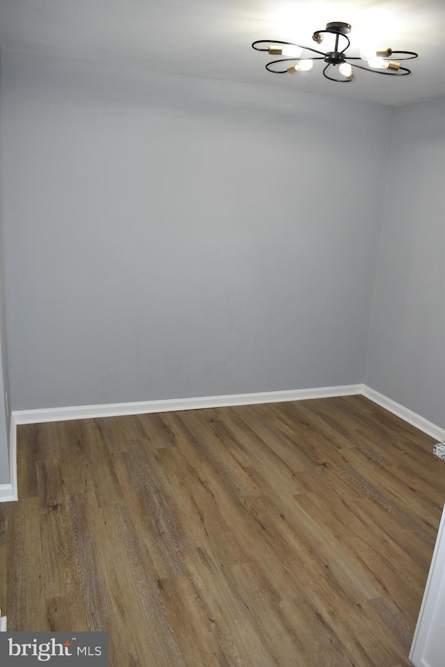 unfurnished room featuring wood-type flooring and a chandelier