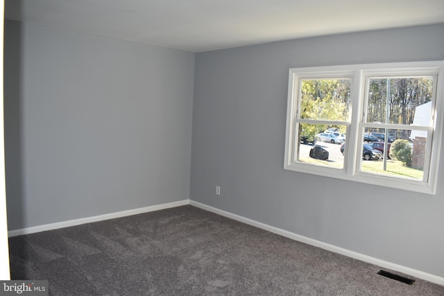 spare room featuring dark colored carpet