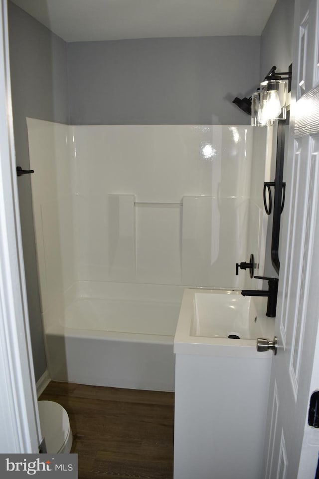 full bathroom featuring hardwood / wood-style flooring, vanity, toilet, and washtub / shower combination