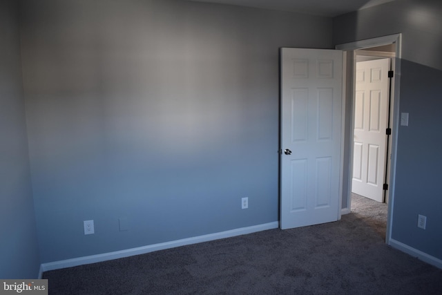 unfurnished room featuring dark colored carpet