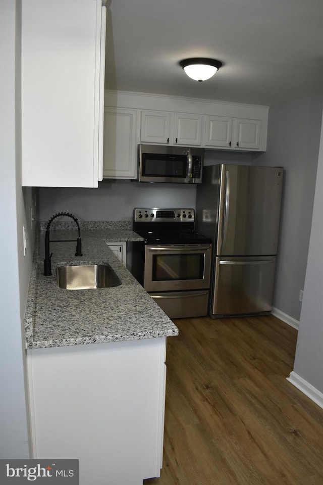 kitchen with light stone countertops, appliances with stainless steel finishes, dark wood-type flooring, sink, and white cabinets