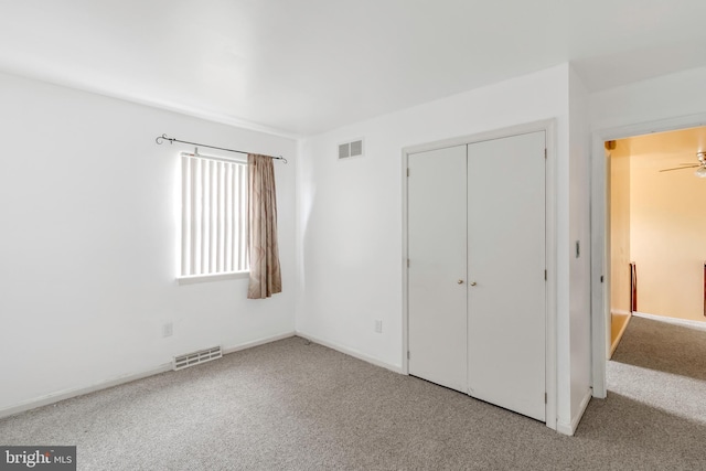 unfurnished bedroom with light colored carpet and a closet