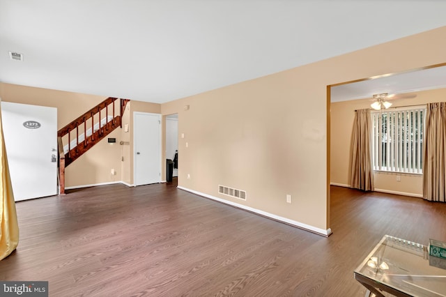 unfurnished living room featuring ceiling fan and dark wood-type flooring