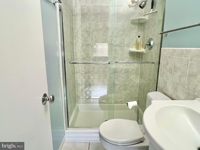 bathroom featuring tile patterned floors, walk in shower, sink, tile walls, and toilet