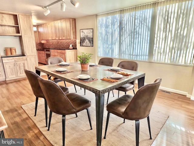 dining room with light hardwood / wood-style flooring and track lighting