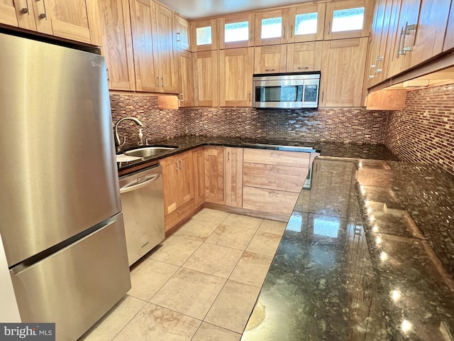 kitchen with decorative backsplash, appliances with stainless steel finishes, sink, dark stone countertops, and light tile patterned flooring