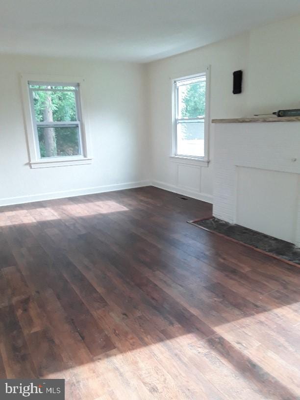 unfurnished room with plenty of natural light and dark wood-type flooring