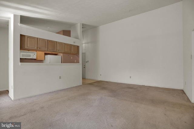 unfurnished living room with light colored carpet and lofted ceiling