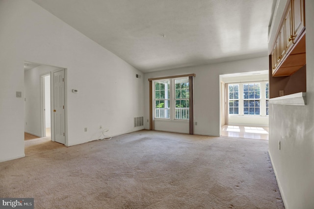 unfurnished living room featuring lofted ceiling and light carpet