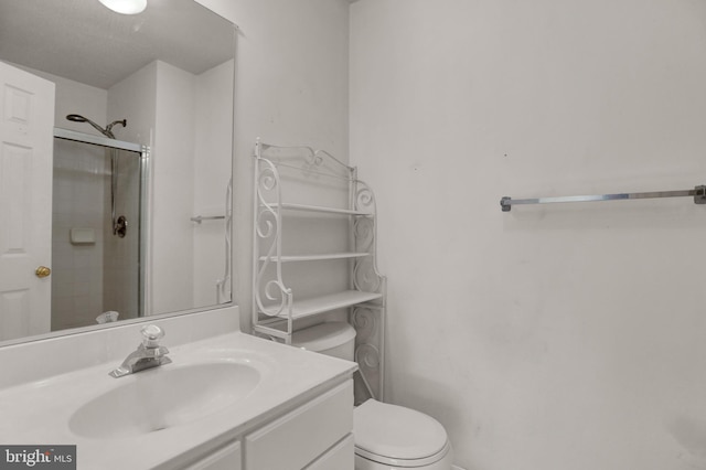 bathroom featuring vanity, a shower with shower door, and toilet