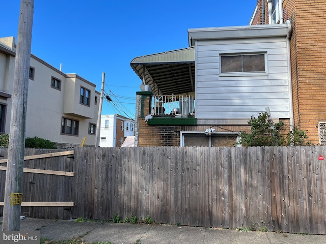 view of home's exterior featuring fence, a balcony, and brick siding