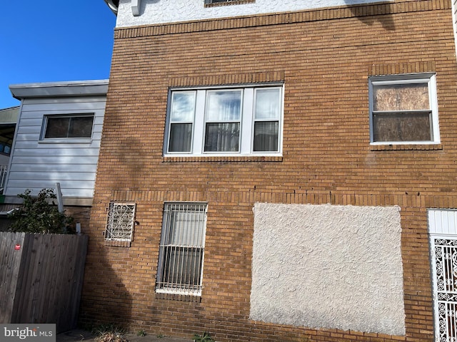 view of side of home with brick siding and fence