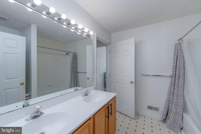 bathroom with shower / bathtub combination with curtain, vanity, and a textured ceiling