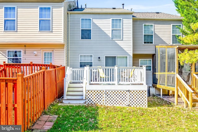 rear view of property featuring a sunroom, a deck, and a lawn