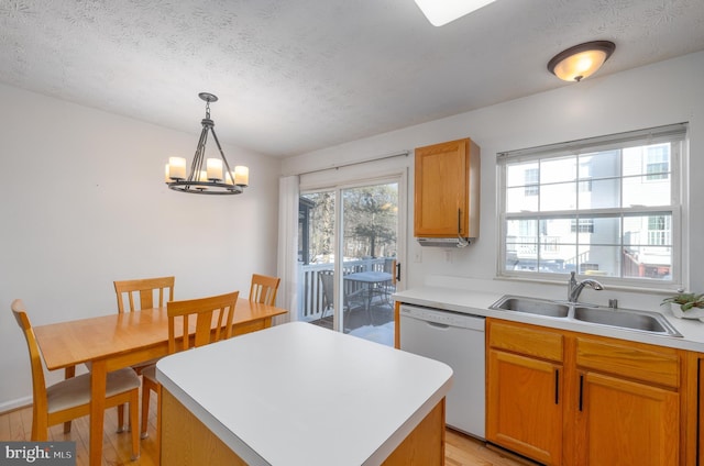 kitchen featuring sink, white dishwasher, a textured ceiling, a kitchen island, and decorative light fixtures