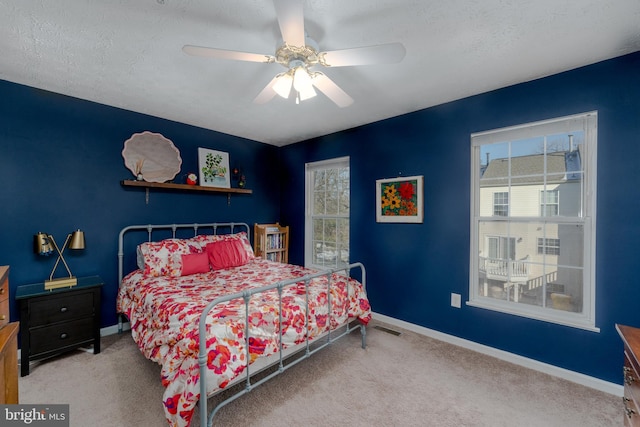 carpeted bedroom featuring multiple windows, ceiling fan, and a textured ceiling