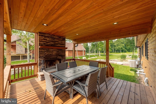 wooden deck with an outdoor stone fireplace, a yard, and central AC unit