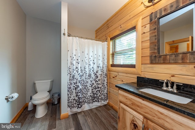 bathroom with hardwood / wood-style flooring, vanity, toilet, and wooden walls