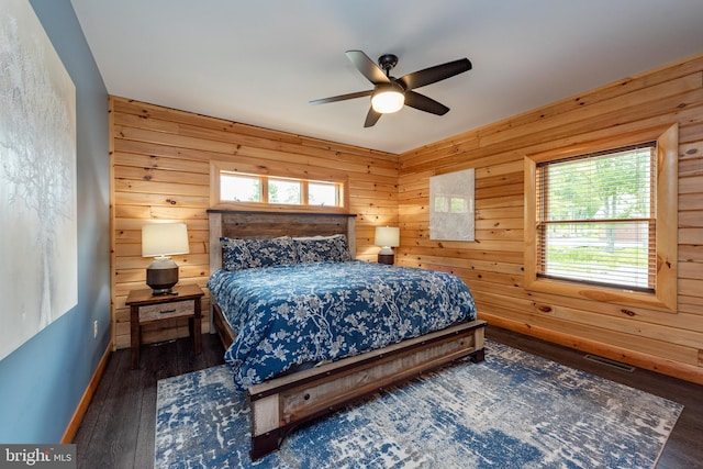 bedroom with dark hardwood / wood-style floors, ceiling fan, and wood walls