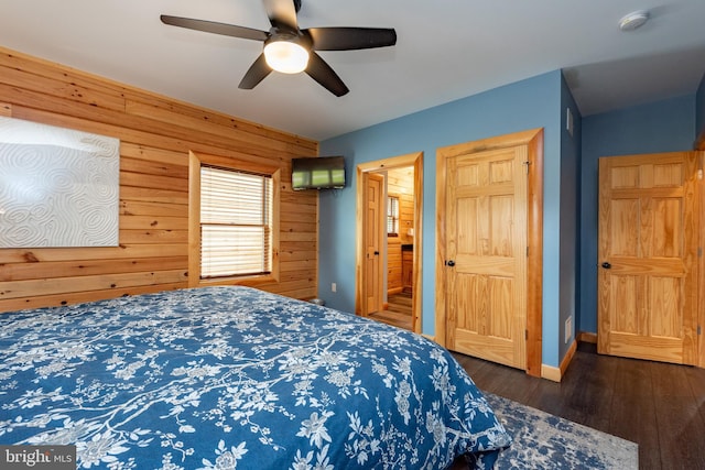 bedroom featuring ceiling fan, dark wood-type flooring, and wooden walls