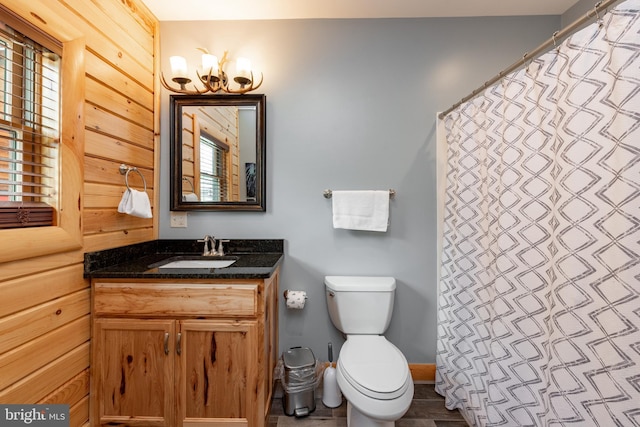 bathroom featuring vanity, toilet, plenty of natural light, and wood walls