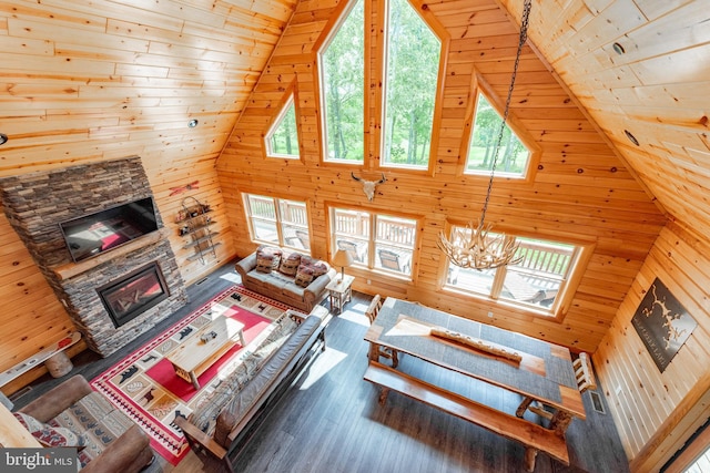 living room with a chandelier, hardwood / wood-style floors, a stone fireplace, and wooden ceiling