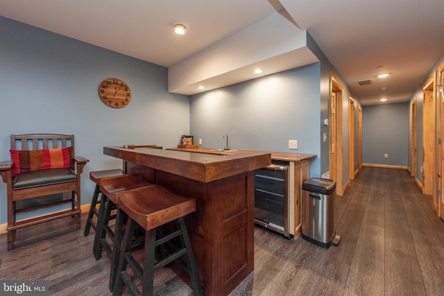 bar featuring dark hardwood / wood-style floors and beverage cooler