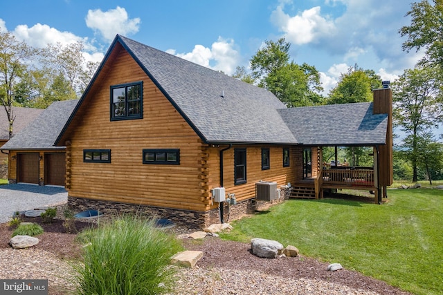 view of front of house featuring a garage, a front lawn, and central air condition unit